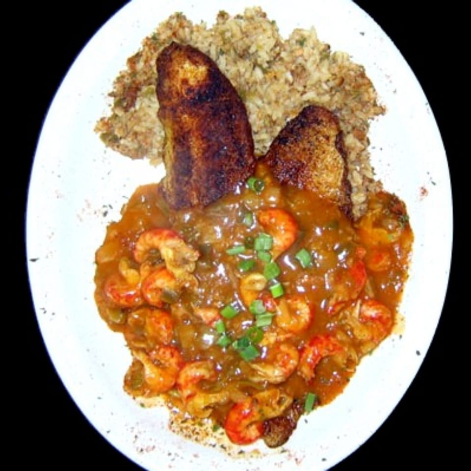 Plate of shrimp in spicy sauce with rice, fried plantains, and chopped green onions.