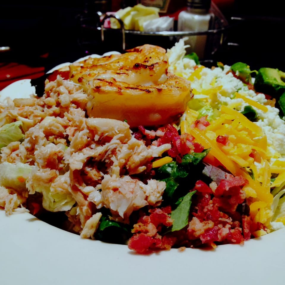 Grilled chicken breast served with rice, shredded chicken, lettuce, tomatoes, peppers, and mixed vegetables on a plate.