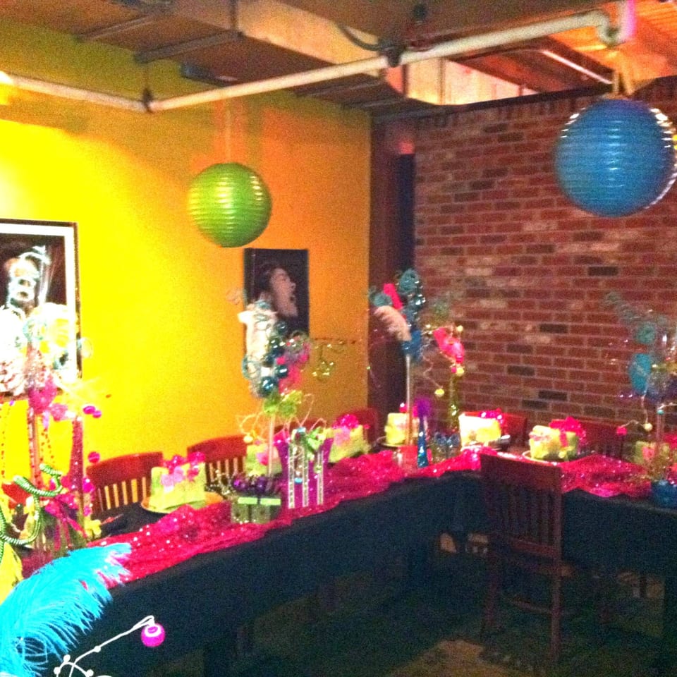 Colorful restaurant dining area decorated with balloons, flowers, patterned tables, and vibrant pink and blue accents.